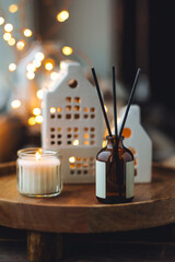 Christmas home aromatherapy. Aroma diffuser with organic essential oil, cinnamon, anise, vanilla scent, burning candles on wooden tray. Cozy atmosphere, holiday spirit. Winter inspiration and mood