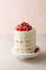 Semi naked red velvet cake with cream cheese frosting decorated with fresh raspberries and currants. Festive layered sponge cake. Traditional American dessert. Selective focus.