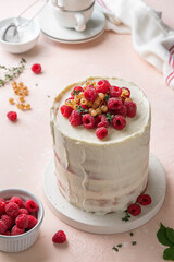 Semi naked red velvet cake with cream cheese frosting decorated with fresh raspberries and currants. Festive layered sponge cake. Traditional American dessert. Selective focus.