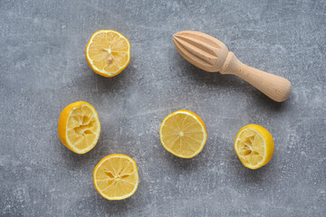 Leftover lemon peels and wooden squizer on gray background.