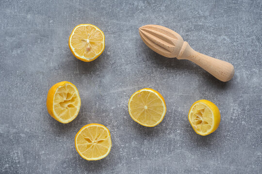 Leftover lemon peels and wooden squizer on gray background.