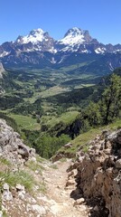 Obraz premium Spectacular Mountain Pathway in the Italian Dolomites with Majestic Snowcapped Peaks, Green Hills, Rocky Trail, Clear Sky, and Lush Forest Valley Views