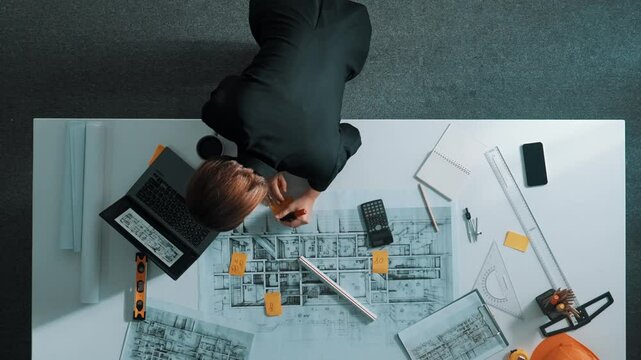 Time lapse of skilled project manager holding project plan and explain house design to architect engineer at meeting table with equipment, ruler, safety helmet and laptop scatter around. Alimentation.