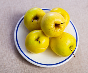 There is plate with fruits and juicy large apples on table.