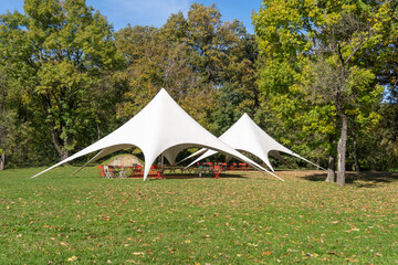 Outdoor white event tent with colorful chairs in the park © ZenitX
