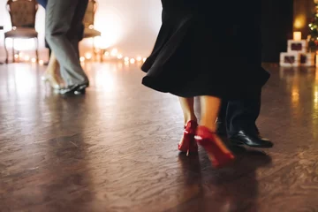 Dancing stiletto shoes of couples dancing traditional latin argentinian dance milonga in the ballroom, tango salsa bachata kizomba lesson in red and purple lights, evening dance school class festival