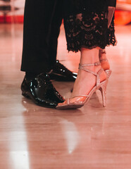Dancing stiletto shoes of couples dancing traditional latin argentinian dance milonga in the ballroom, tango salsa bachata kizomba lesson in red and purple lights, evening dance school class festival