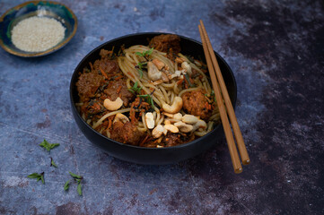 Vegan noodles and seitan stir fry on gray table, copy space