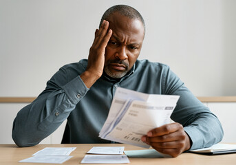 Worried manager reviewing receipts, calculating domestic bills, experiencing financial problems, suffering from migraine