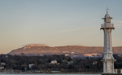 The lighthouse of Bains des Paquis, in Geneva, with the Alpine foothills in the background, on a sunny afternoon