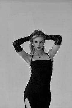 Beautiful girl blonde in a black dress posing on a gray background