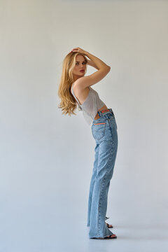 Beautiful girl blonde in jeans posing in the studio on a white background