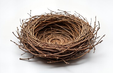 Obraz premium Empty bird nest made of twigs sits on white background. Natural material creates cozy home. Perfect for nature theme designs. Suitable for various springtime themes. Ideal for eco-friendly products.