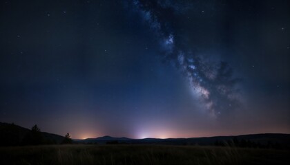 Stunning night sky scene shows Milky Way galaxy stretching across starry night sky above silhouette landscape. Silhouette of distant mountains, grasses form horizon. Cosmic view of beautiful night
