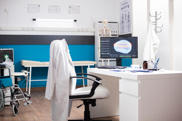 Modern clinic workstation features desktop pc displaying brain scan with organized desk in clean empty office. Computer monitor in hospital room is showing diagnostic results for neurological tests.