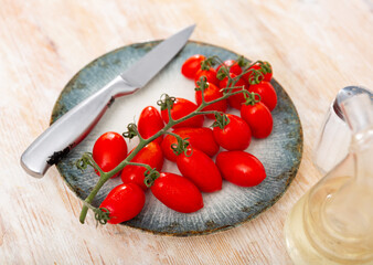 Fresh bunch of cherry tomatoes on plate on wooden table
