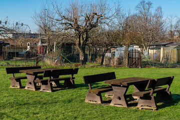 Picnic tables in a sunny park surrounded by trees and gardens