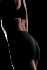 Naklejka premium Athletic woman's back and toned physique captured in low-light studio