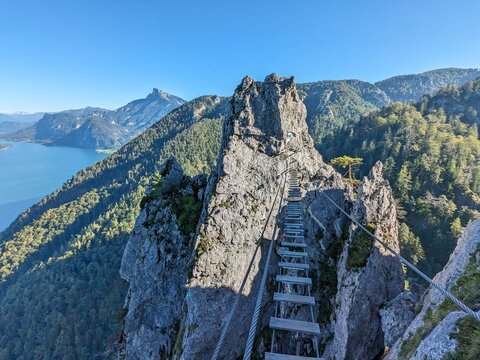 Fototapeta Rope suspension bridge on VIA FERRATA in Austria with stunning blue lake and alpine mountain peaks in the background