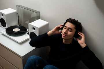 Man is relaxing with vinyl rock records from speaker system at home. Listen and enjoy 78 RMP...