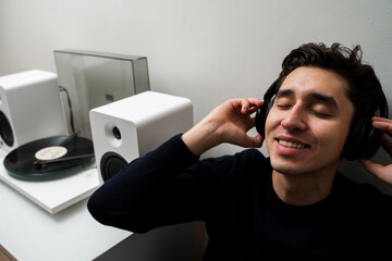 Cheerful musician with headphones is listening a retro vinyl record at home. Vinyl music lover....