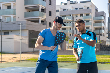 Two male pickleball players discussing strategy on court