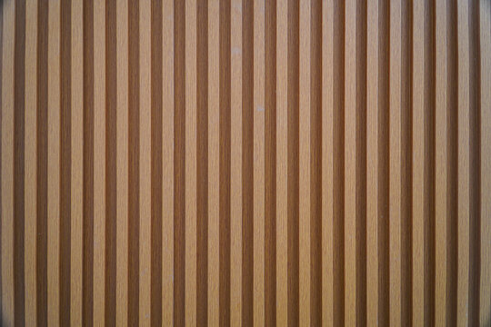 Close-up image of a wooden panel with vertical stripes. The texture is smooth and even, ideal as a background. Striped Wooden Panel Texture: A Close-Up View of Vertical Lines