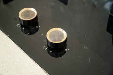 Image shows two knobs on a sleek, black glass stovetop. The gold accents on the knobs add a touch...