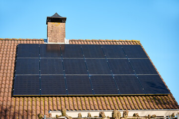 Solar panels on red tile roof close up, blue sky background