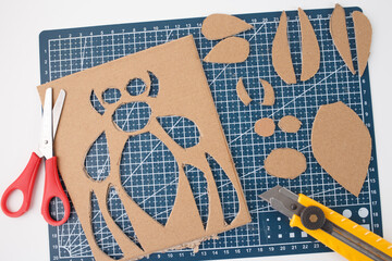 cutting mat with tools, scissors, utility knife, the organized cardboard cutouts cardboard insect,