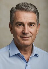 Obraz premium Confident mature male in blue shirt with gray hair smiling warmly at camera