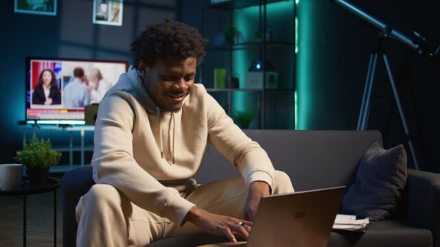 African american male freelancer managing creative projects remotely in his loft, working on a new novel or script for his gig. Man focusing on writing and editing creation, telework. Camera B.