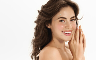 Portrait of smiling woman with glowing healthy skin, applied delicate face gems for a festive Valentines Day look. Female model posing for beauty photo on white studio background