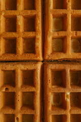 Golden-brown crispy waffles in a close-up shot. Detailed texture with a crisp outer layer and soft interior. Freshly baked breakfast food with a warm and inviting appearance