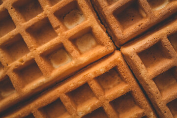 Golden-brown crispy waffles in a close-up shot. Detailed texture with a crisp outer layer and soft...