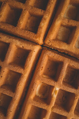 Golden-brown crispy waffles in a close-up shot. Detailed texture with a crisp outer layer and soft interior. Freshly baked breakfast food with a warm and inviting appearance