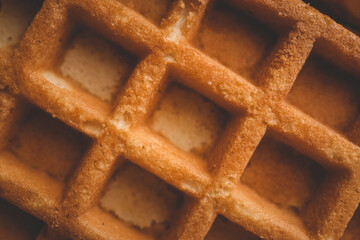 Golden-brown crispy waffles in a close-up shot. Detailed texture with a crisp outer layer and soft interior. Freshly baked breakfast food with a warm and inviting appearance