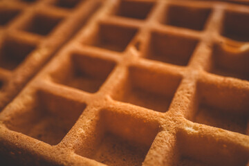 Golden-brown crispy waffles in a close-up shot. Detailed texture with a crisp outer layer and soft interior. Freshly baked breakfast food with a warm and inviting appearance