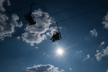 A sunny chairlift ride offers breathtaking views of fluffy clouds and a vibrant blue sky. Pure joy and freedom!