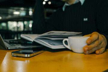 A professional workspace with a person organizing tasks using a notebook, tablet, and laptop on a wooden table, creating a productive and modern office environment