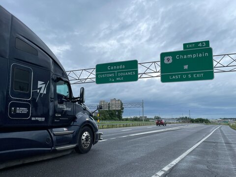 A large tractor trailer drives on the interstate highway, heading towards the US and Canadian boarder near Plattsburgh New York 