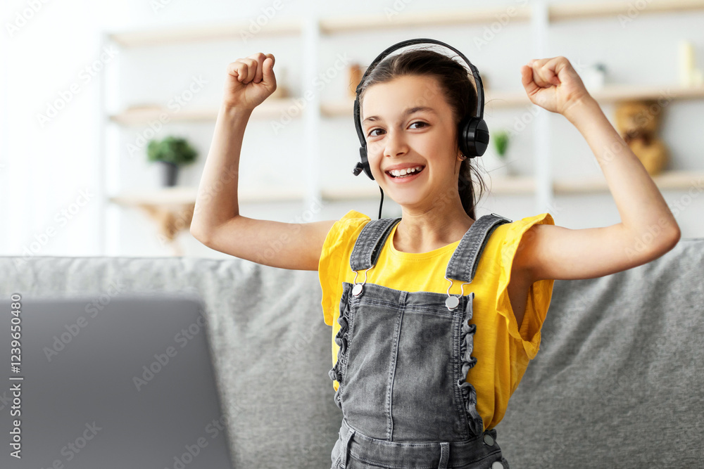 Aufkleber Portrait of smiling child wearing headset showing yes gesture playing online game or studying, shaking and raising clenched fists up in the air, looking at camera, using computer free copy space