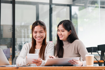 Obraz premium Two women working together in a modern office, using technology and sharing ideas, showcasing teamwork and collaboration.