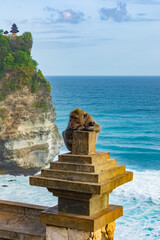 A monkey in Uluwatu Monkey Forest, Badung, Bali. Uluwatu Temple is visible in the background.