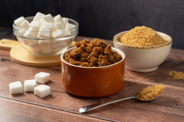 Different type of sugar, light brown, dark brown and white sugar cubes in bowls. 