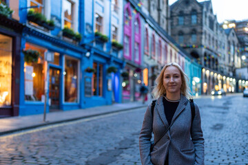 A cheerful woman strolls down a vibrant street, its colorful buildings glowing warmly in the...