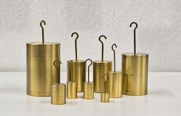Brass hooked weights scientific laboratory measuring equipment on table.	
