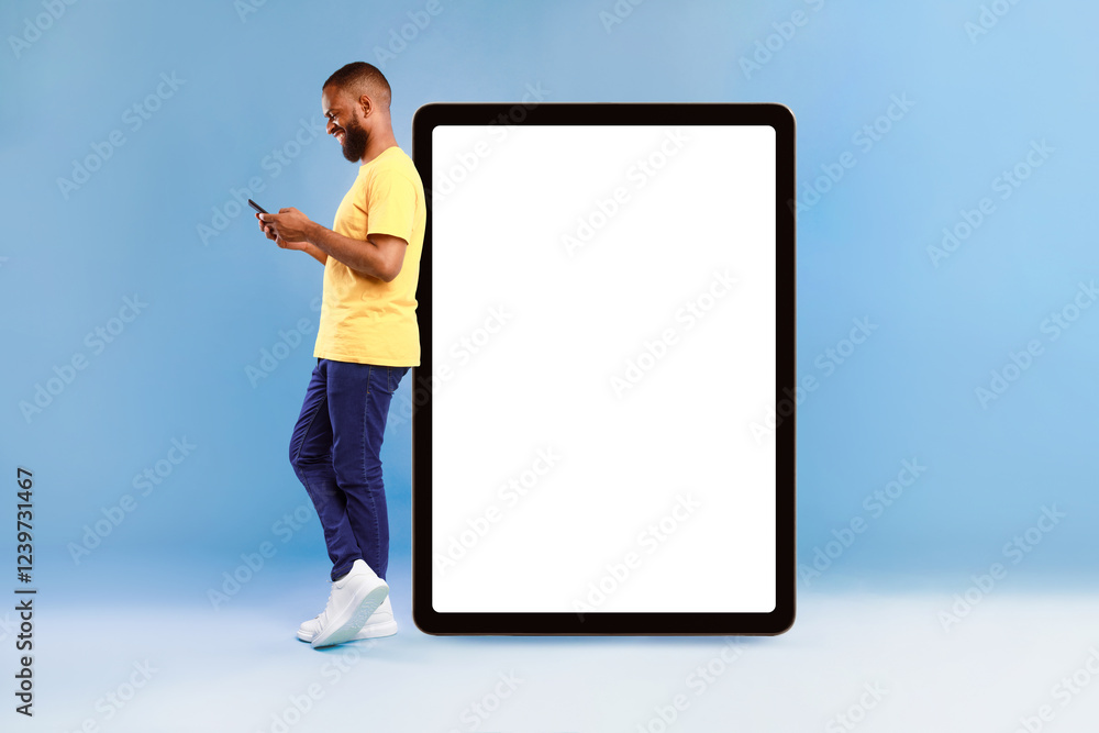 Aufkleber attractive african american man standing near huge digital tablet with empty white screen, using sma