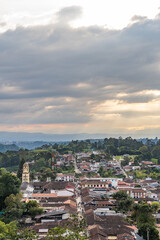 Naklejka premium Salento town at sunset in the mountains of Colombia. Aerial view of the houses and the main church. Busy place for tourism and traveling lifestyle.