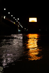 Serene night scene: Orange lights from a bridge beautifully illuminate dark water, creating a captivating reflection.